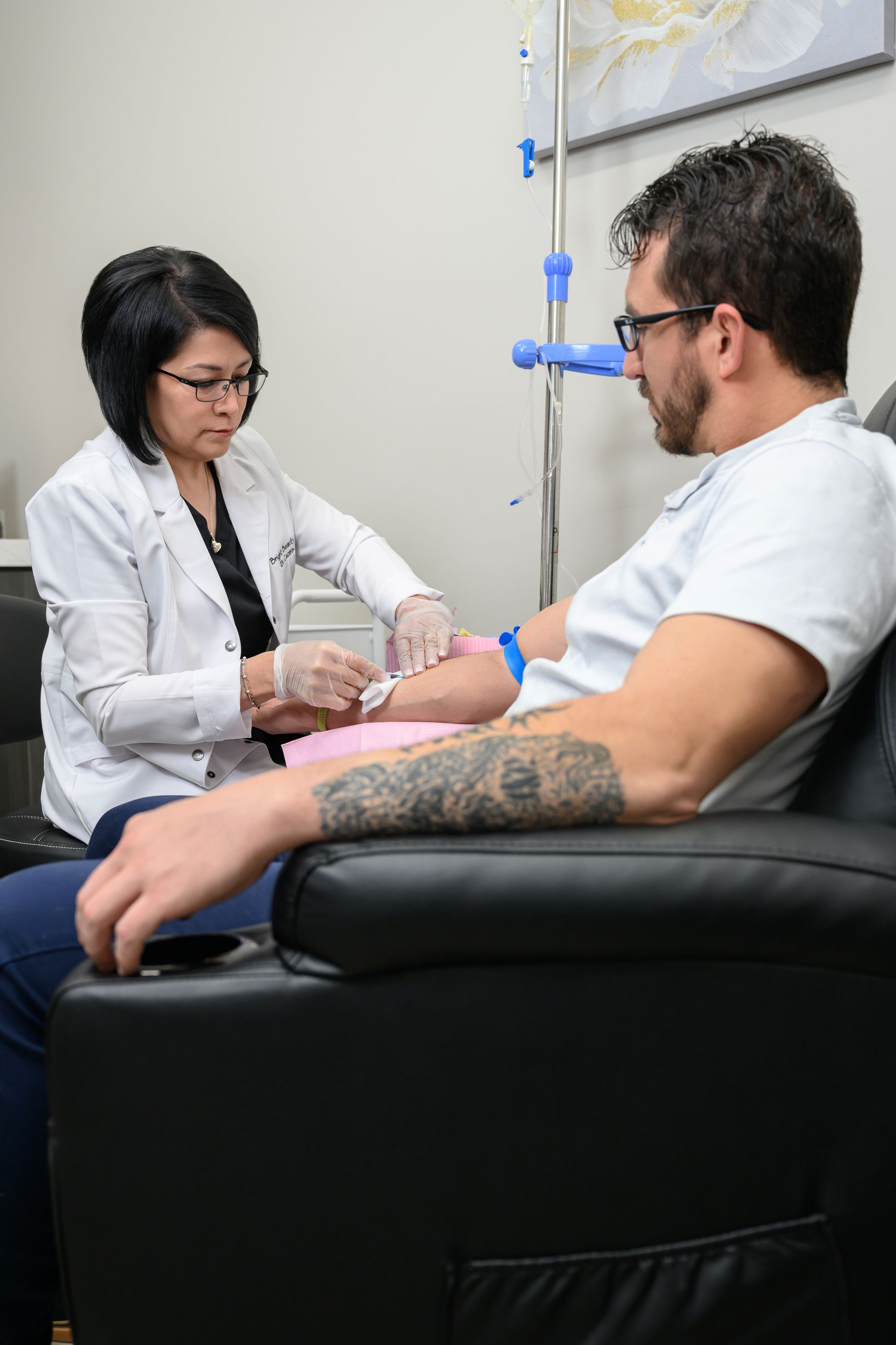 A man is sitting in a chair getting an injection from a doctor.