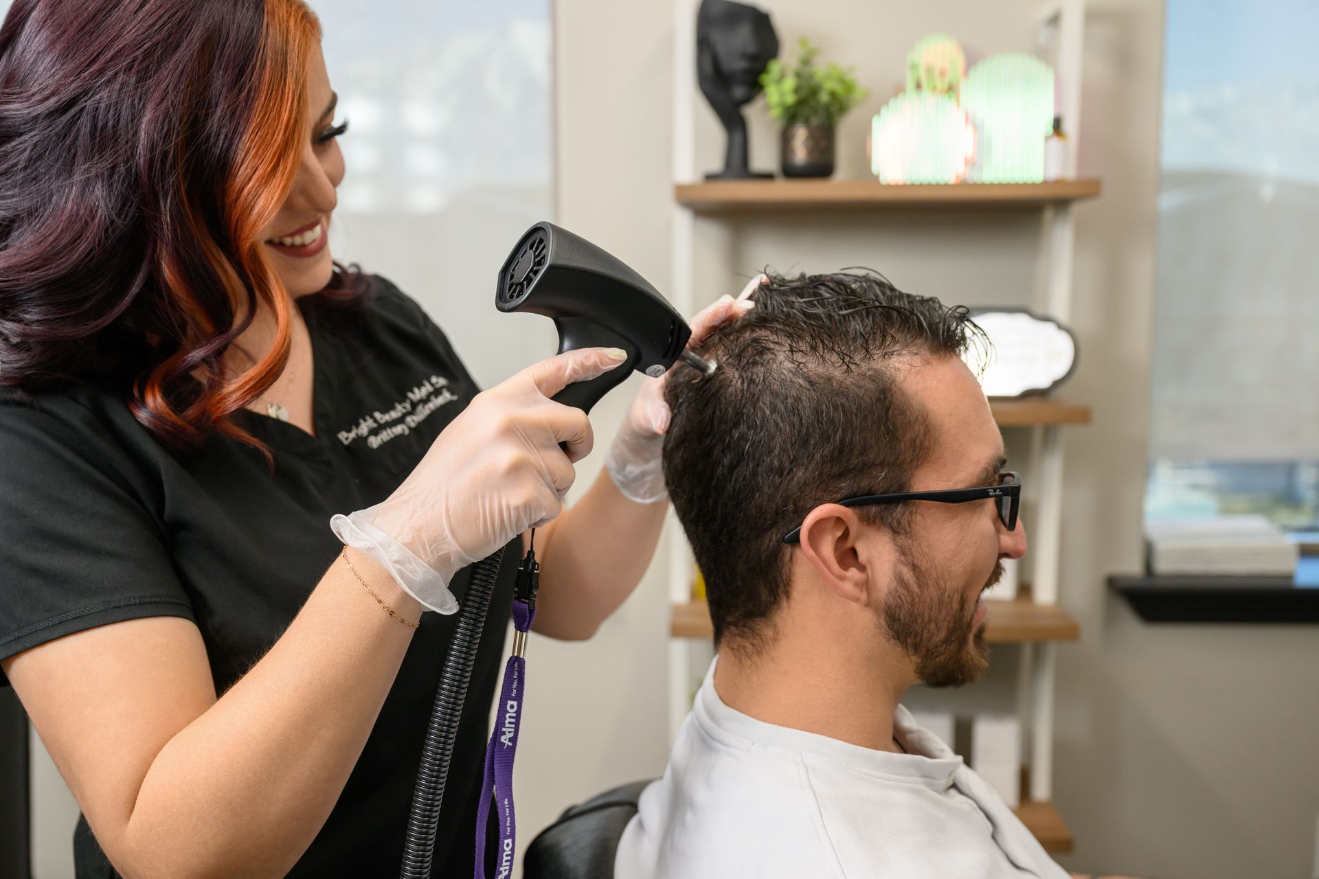 A woman is blow drying a man 's hair in a salon.