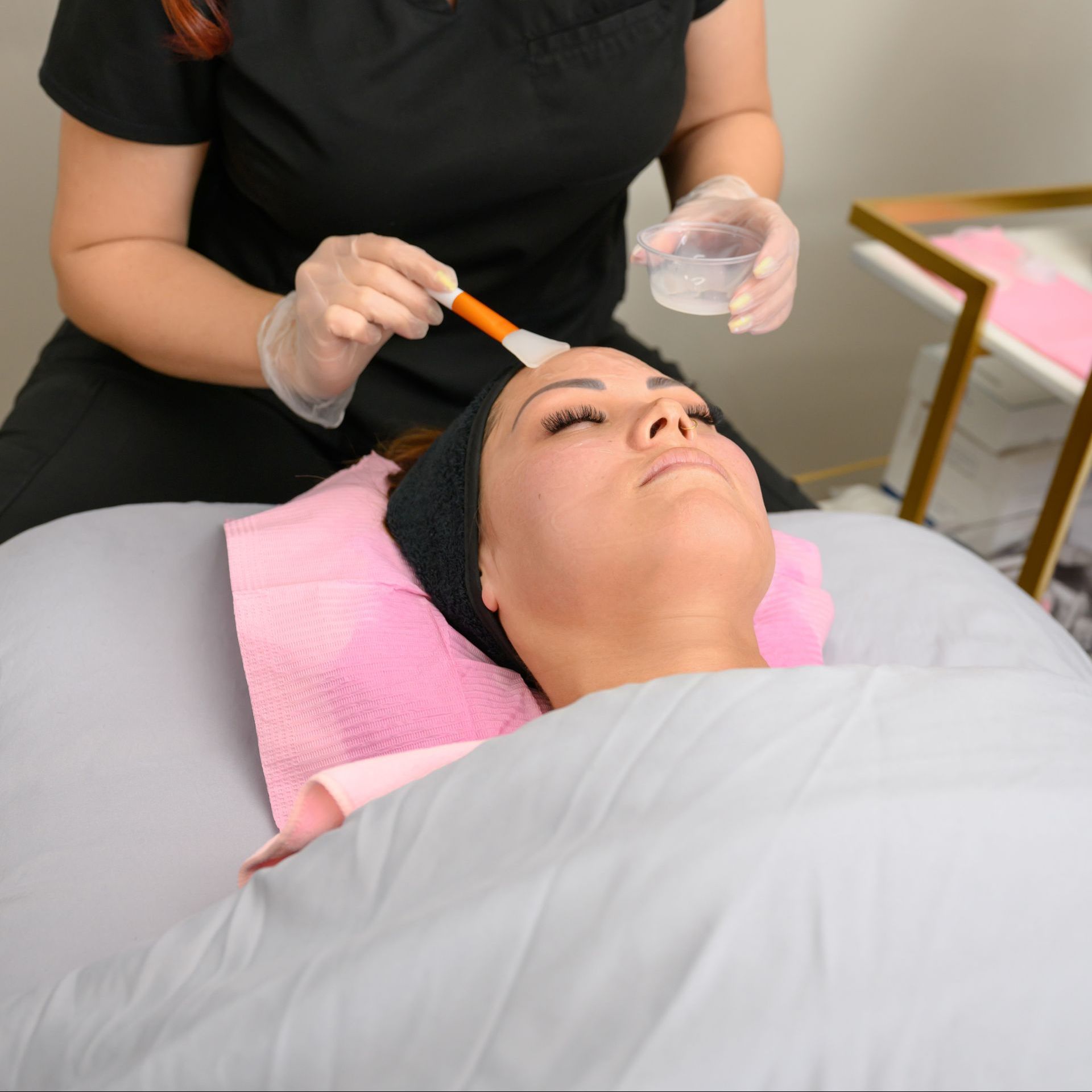 A woman is applying a facial treatment to a woman 's face.