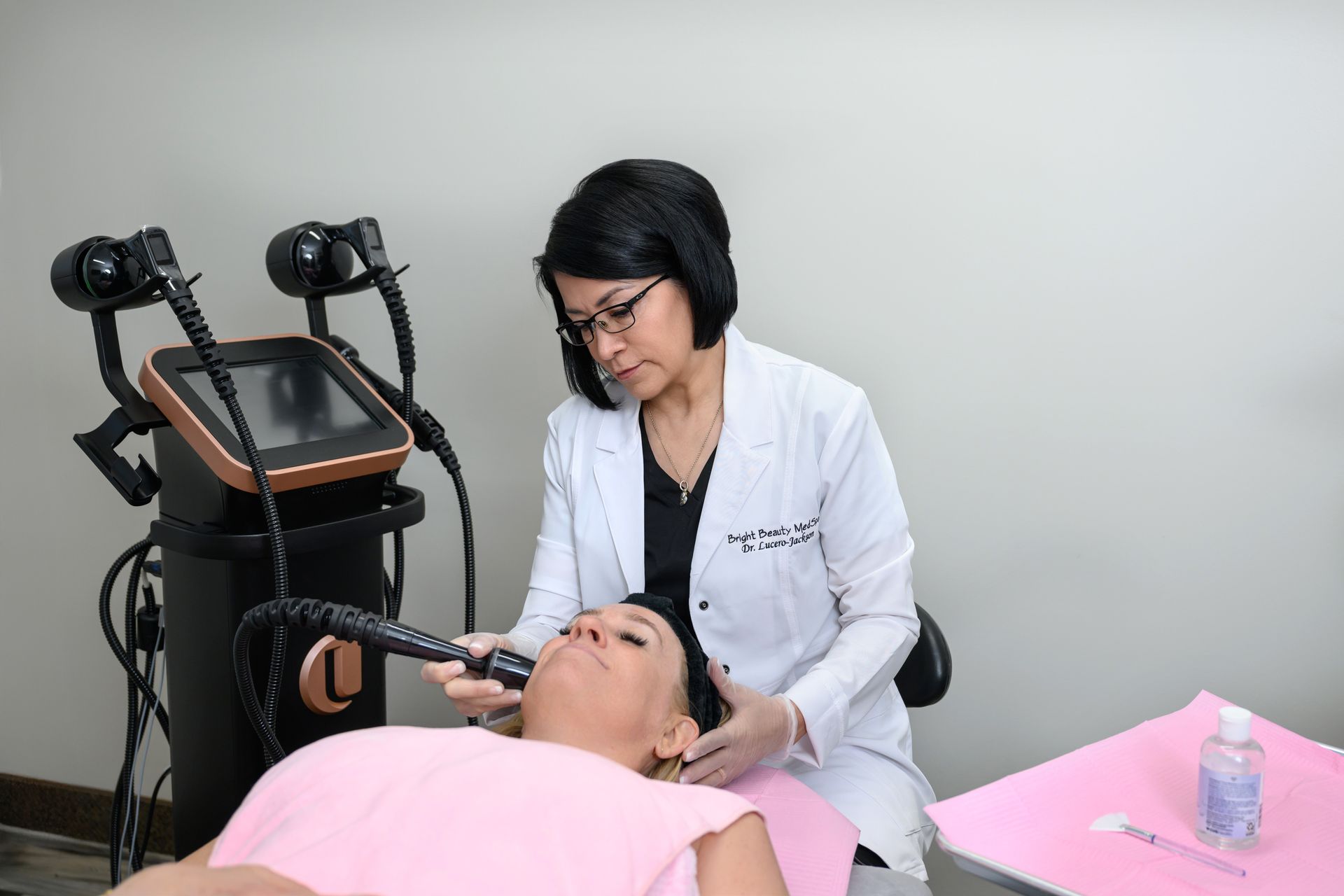 A woman wearing sunglasses is using a machine on a woman 's face.