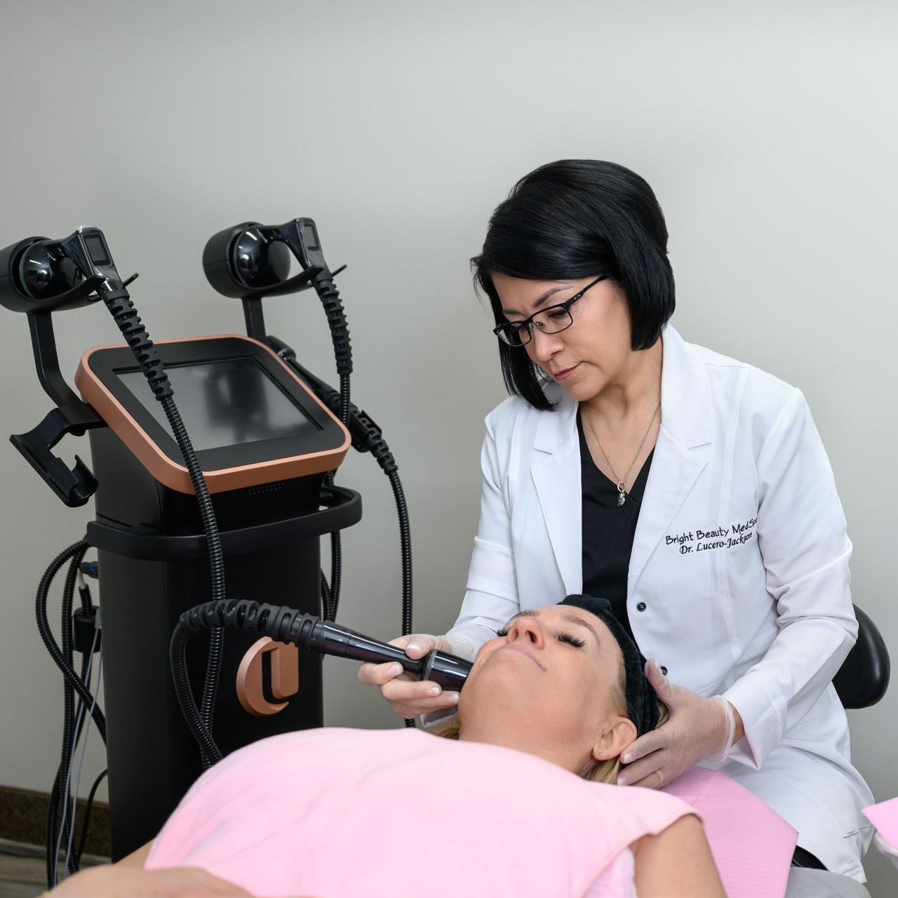 A woman wearing sunglasses is using a machine on a woman 's face.