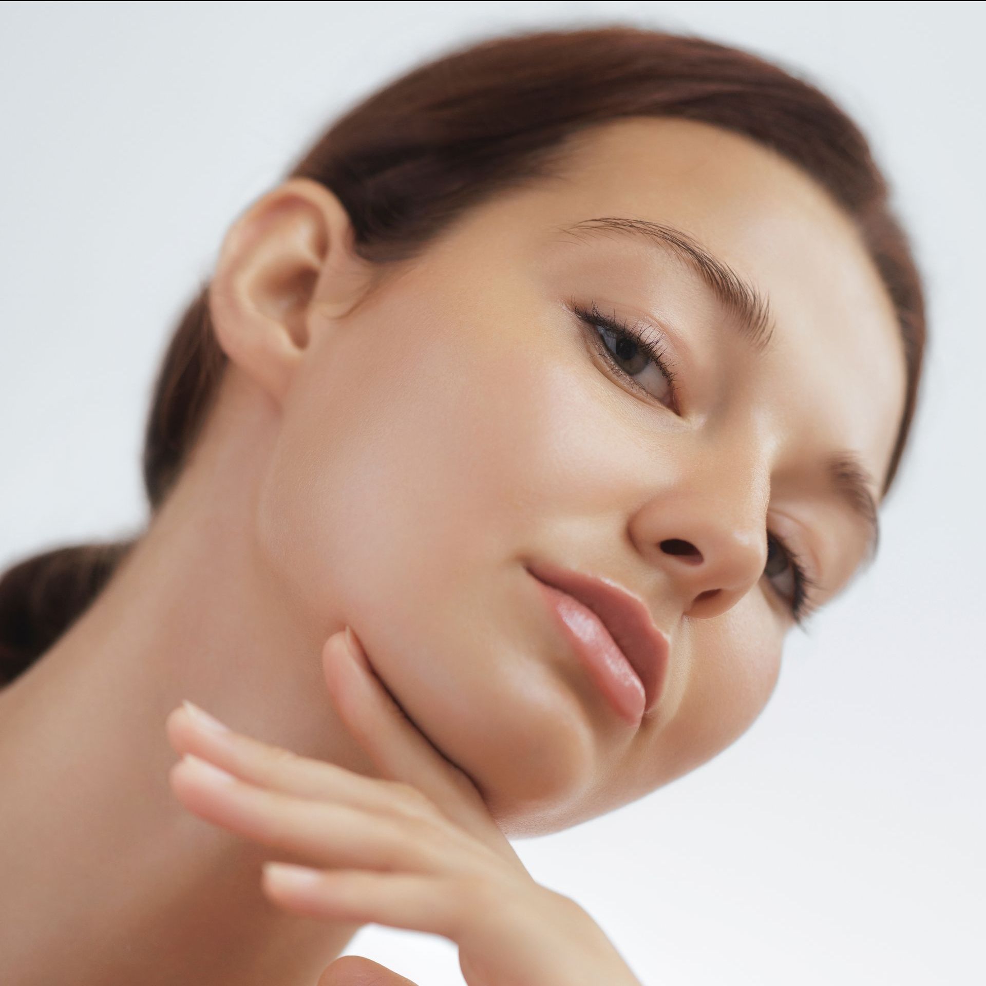 A close up of a woman 's face with her hand on her chin