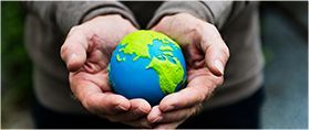 Hands cupping a blue and green Earth globe, symbolizing environmental care.