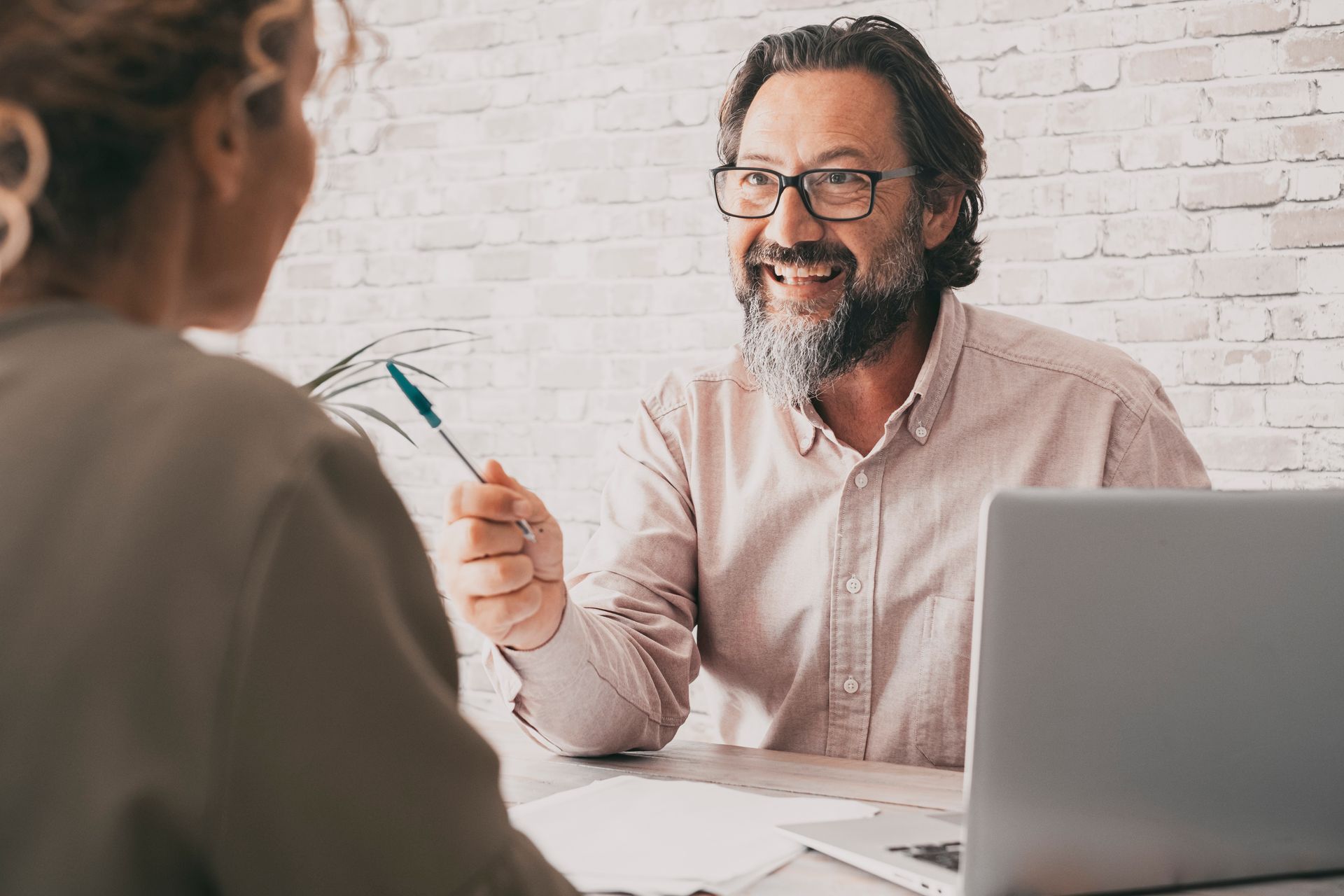 View of a business advisor talking to a businessowner woman with a pen and a laptop.