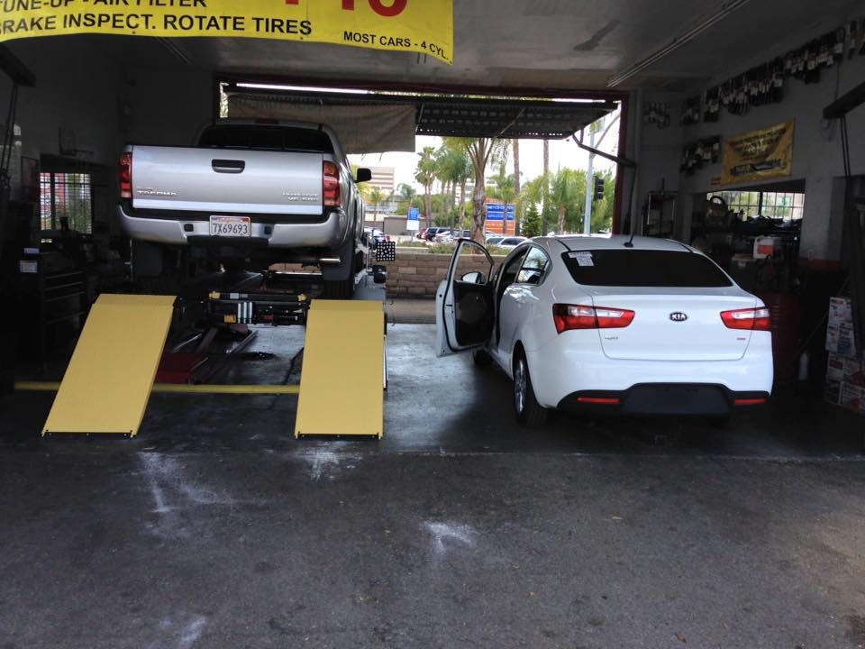 Pickup Truck on Lift and White Sedan Inside Auto Repair Shop | Main Auto Care