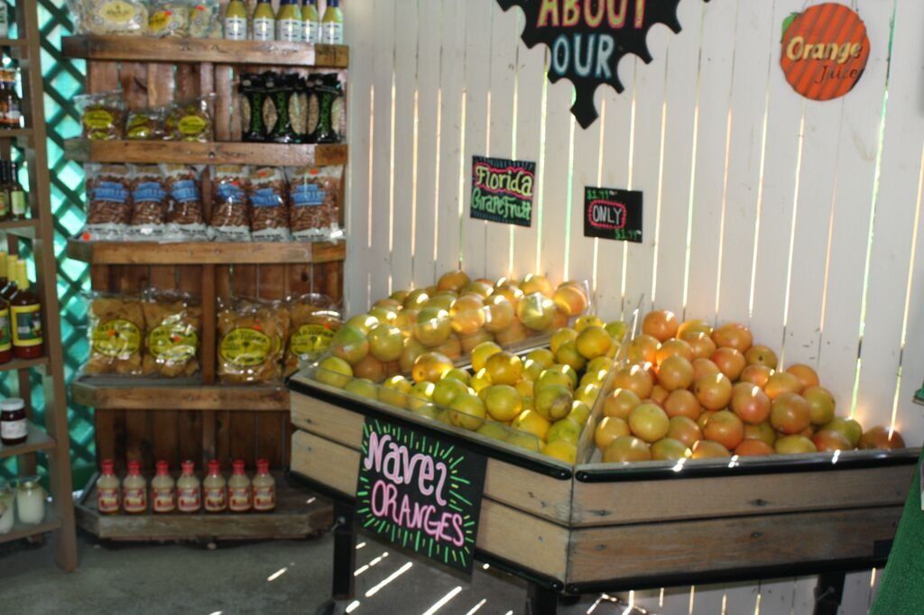 Oranges for sale in a wooden display, with shelves of packaged goods and a sign that says 