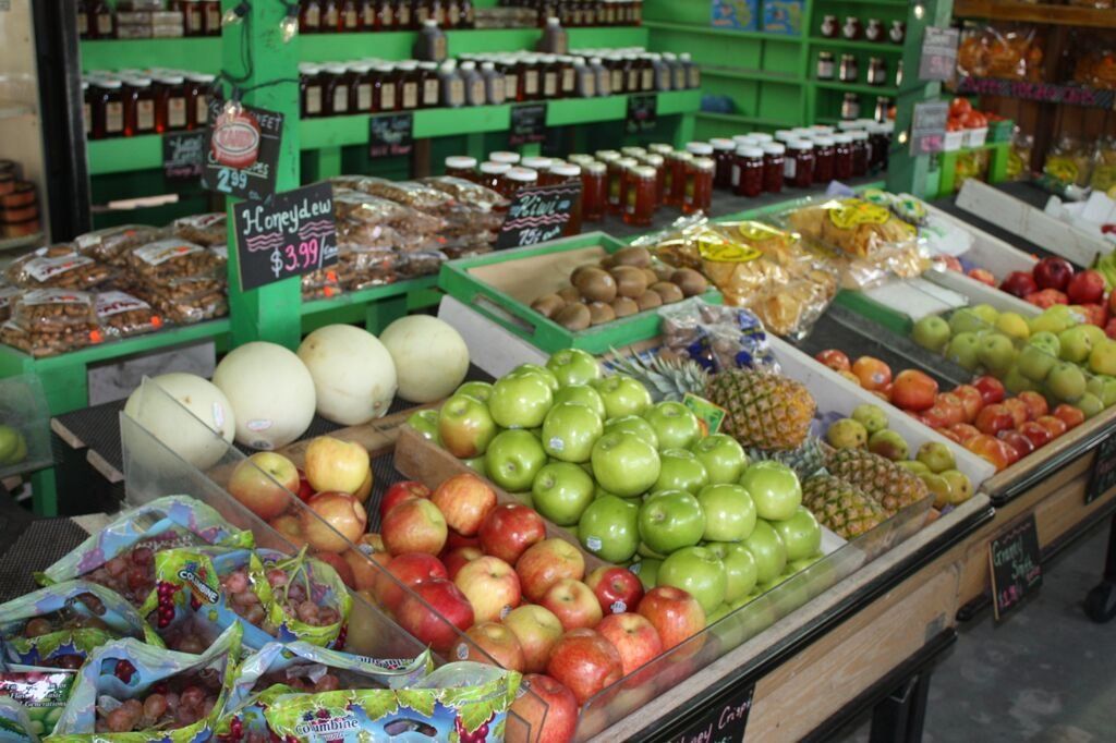 Produce stand with fruits and jars of preserves.