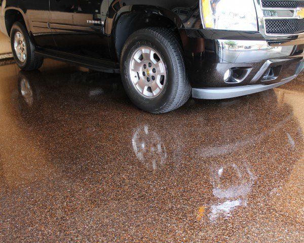 a black suv is parked in a garage with a shiny epoxy floor