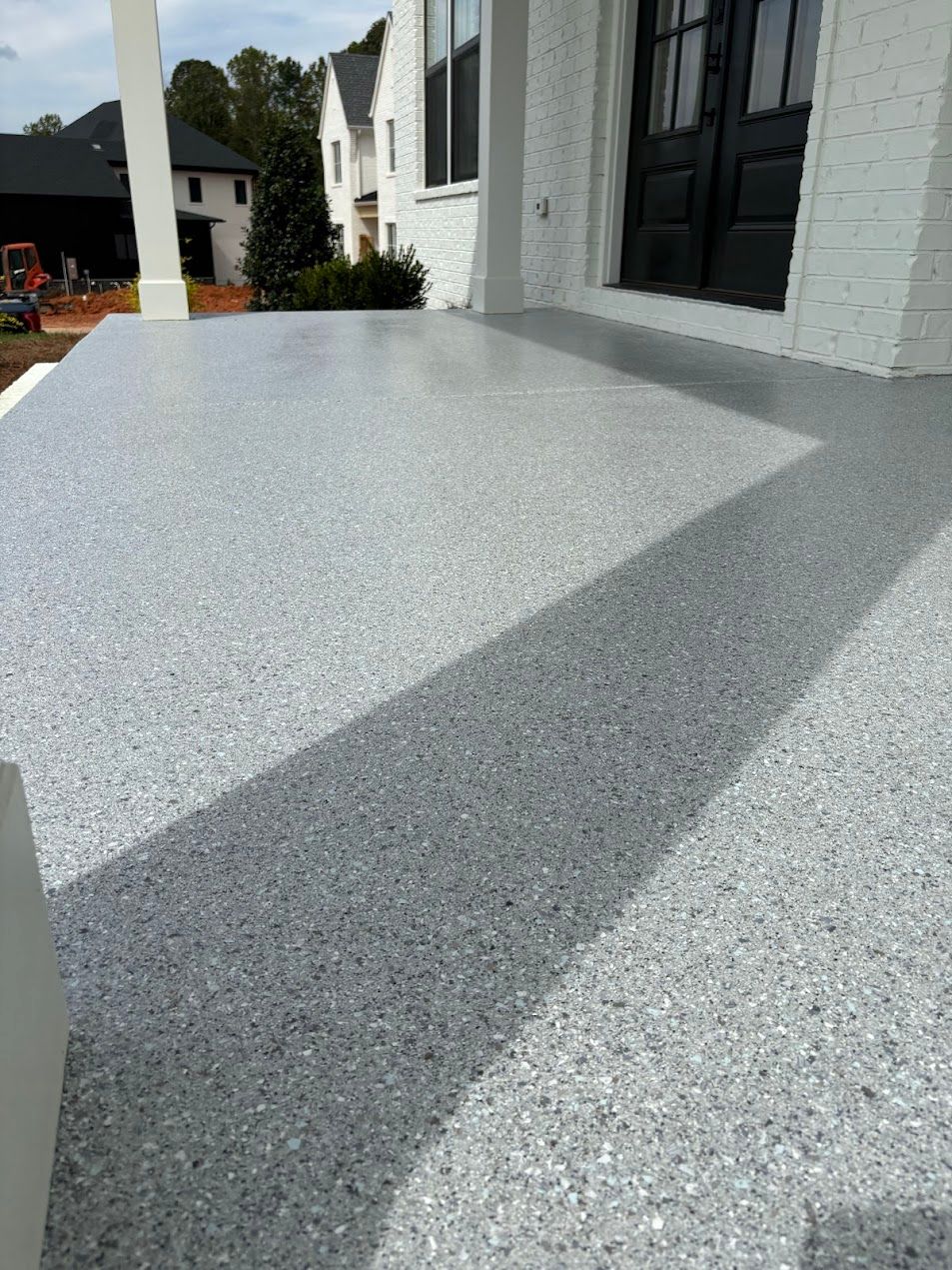 A porch with a gray epoxy floor and a black door.