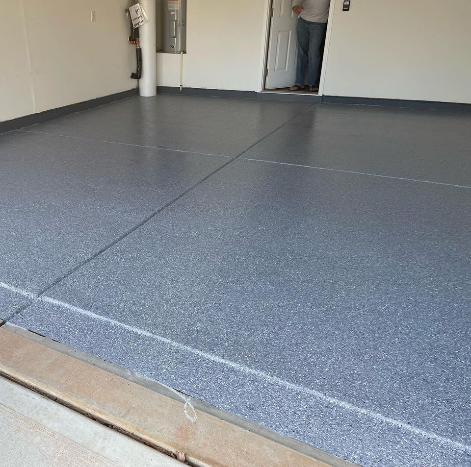 a man is standing in a garage with a gray floor