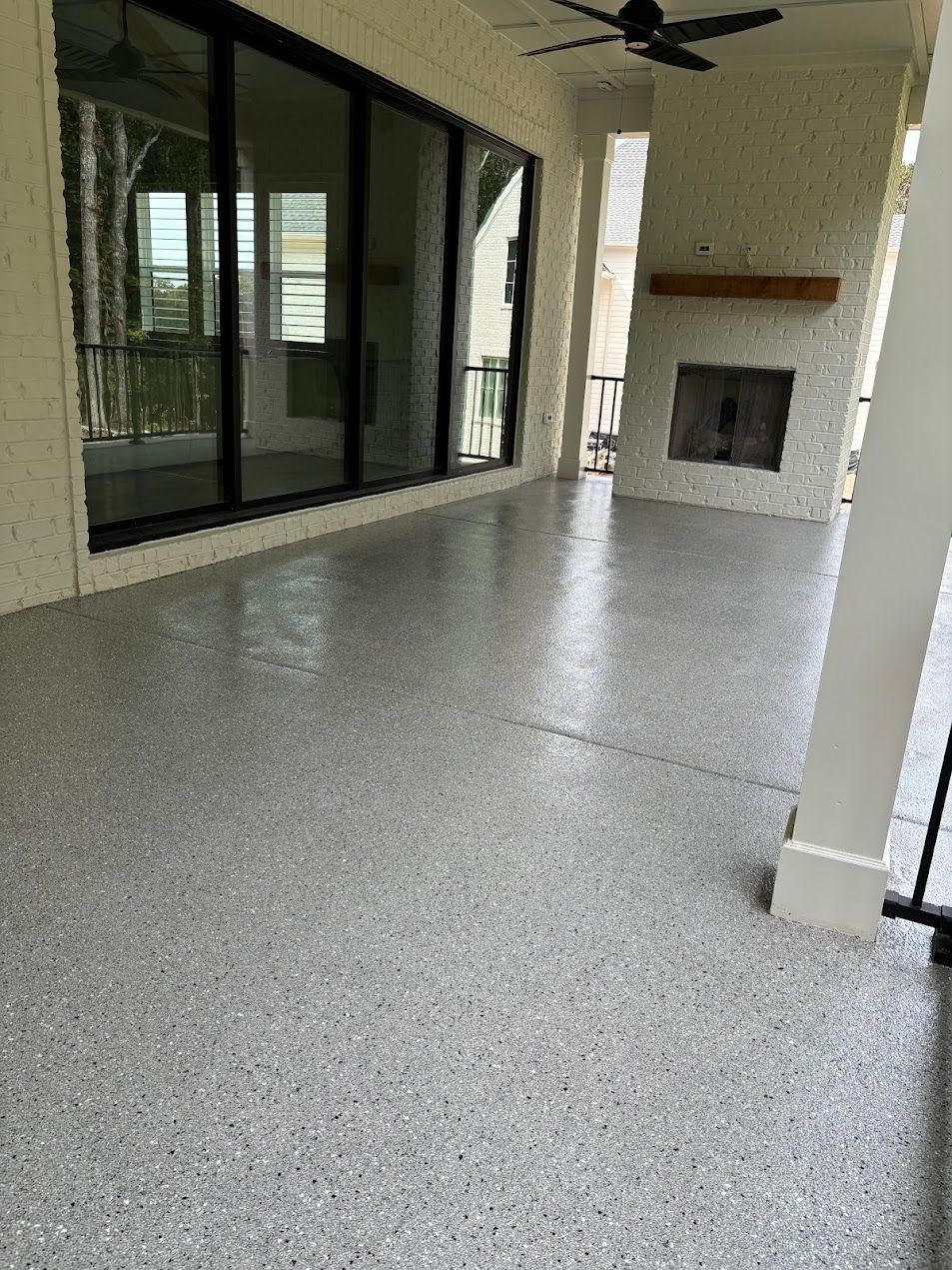 A large patio with epoxy flake floors, a fireplace, and sliding glass doors.