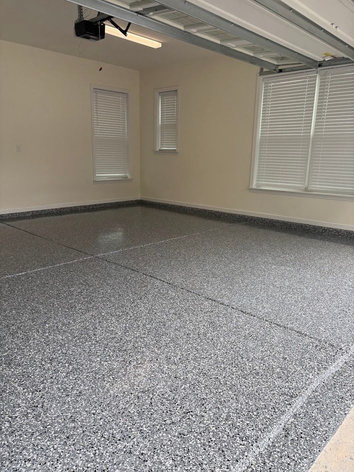 Garage with gray speckled epoxy floor in Huntersville, NC , tan walls, and windows with blinds.