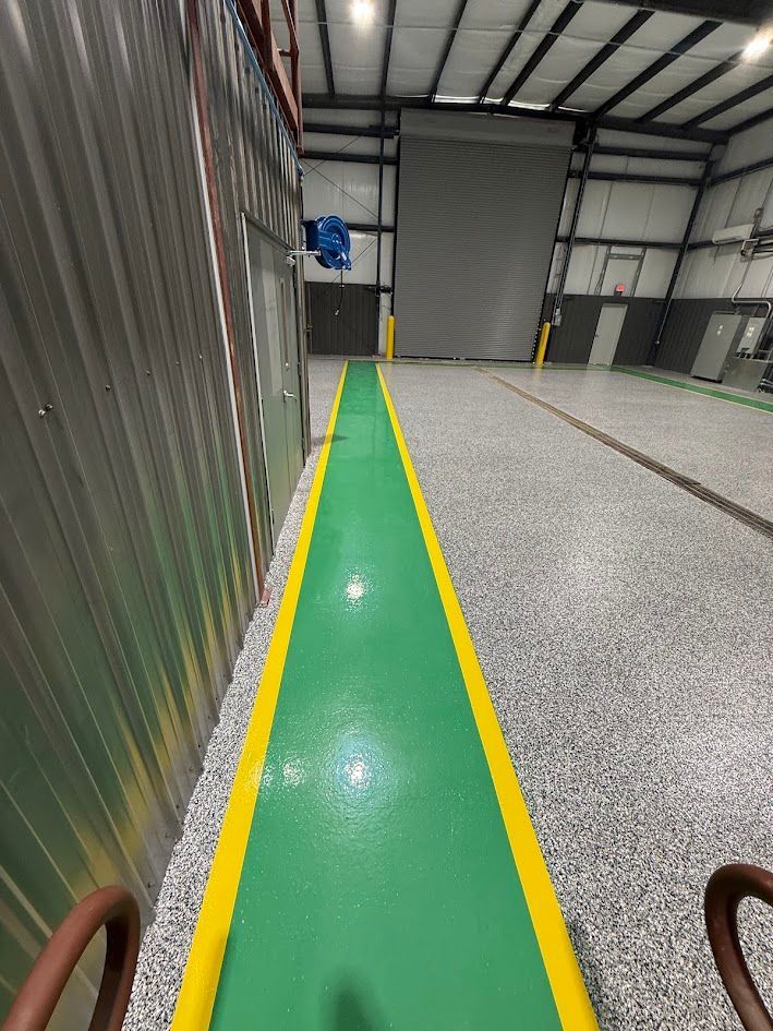 Green walkway with yellow borders inside a garage, leading to a closed door.