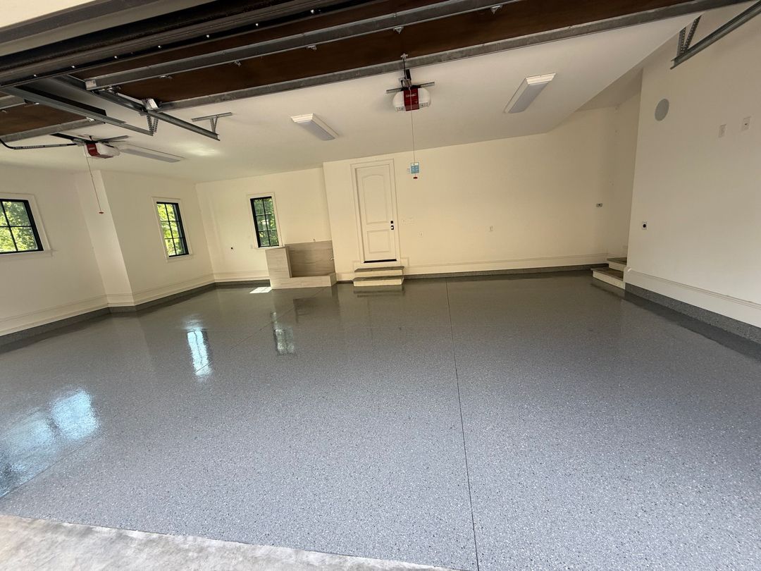 Spacious garage with a gray epoxy floor, white walls, and a closed garage door.