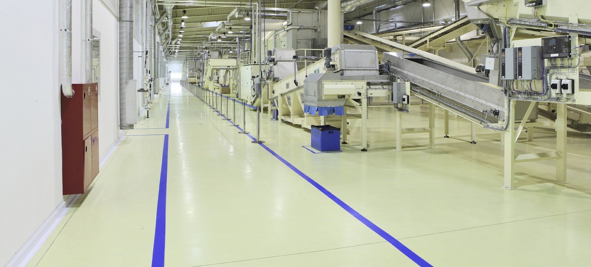 a long hallway in a factory with blue lines on the floor .