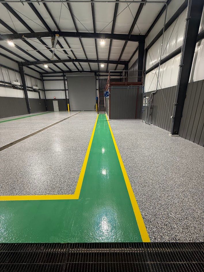 Interior of a commercial building with a green painted path outlined in yellow on the speckled gray floor.