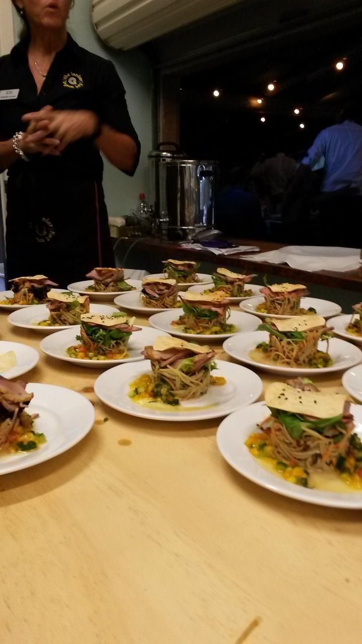A Woman Stands Behind a Table Full of Plates of Food — The Larder Byron Bay in Byron Bay, NSW