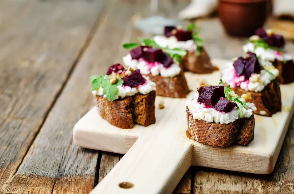 A Wooden Cutting Board Topped With Sandwiches on a Wooden Table — The Larder Byron Bay in Byron Bay, NSW