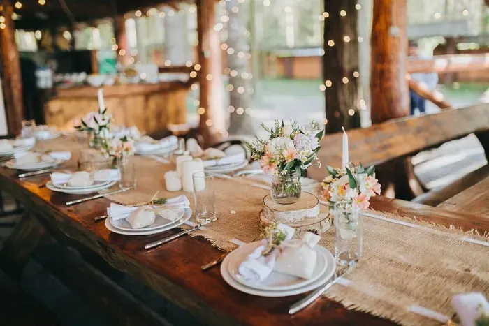 A Long Wooden Table With Plates, Candles, and Flowers on It — The Larder Byron Bay in Byron Bay, NSW