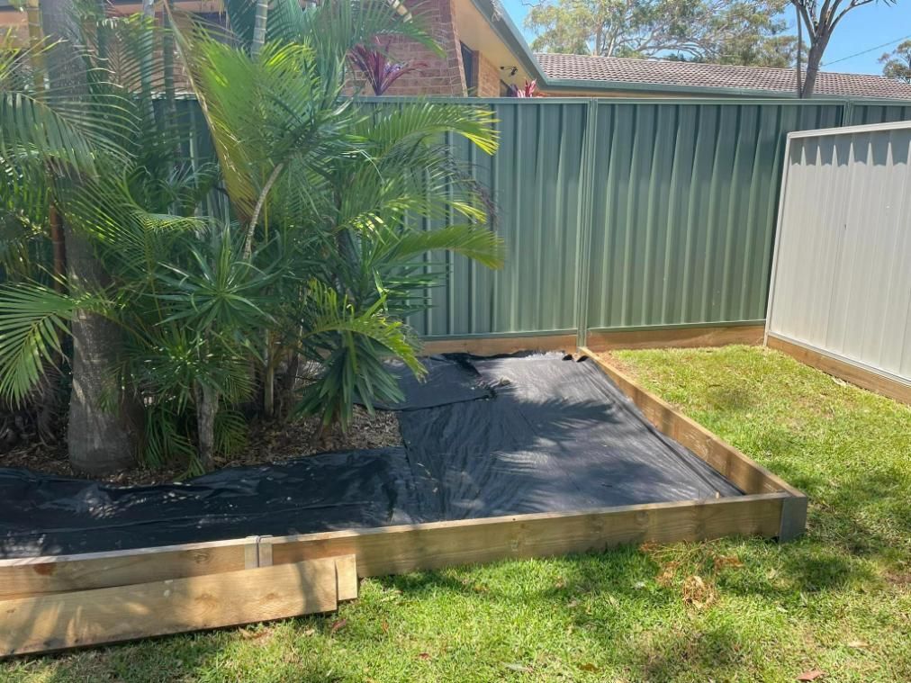 A Backyard With A Fence And A Wooden Planter — Port Tipper & Driver In Port Macquarie, NSW