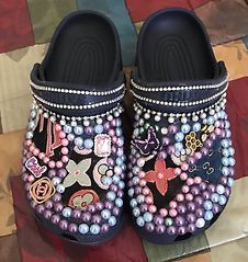 Bedazzled black Crocs adorned with pearls and designer charms.