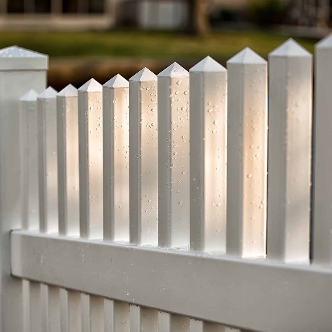 A close up of a white picket fence with water drops on it.