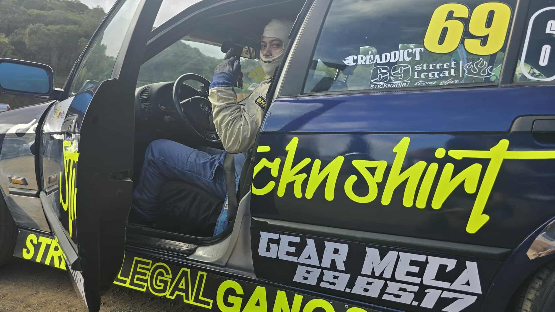 Person in racing car, door open. Blue car with 