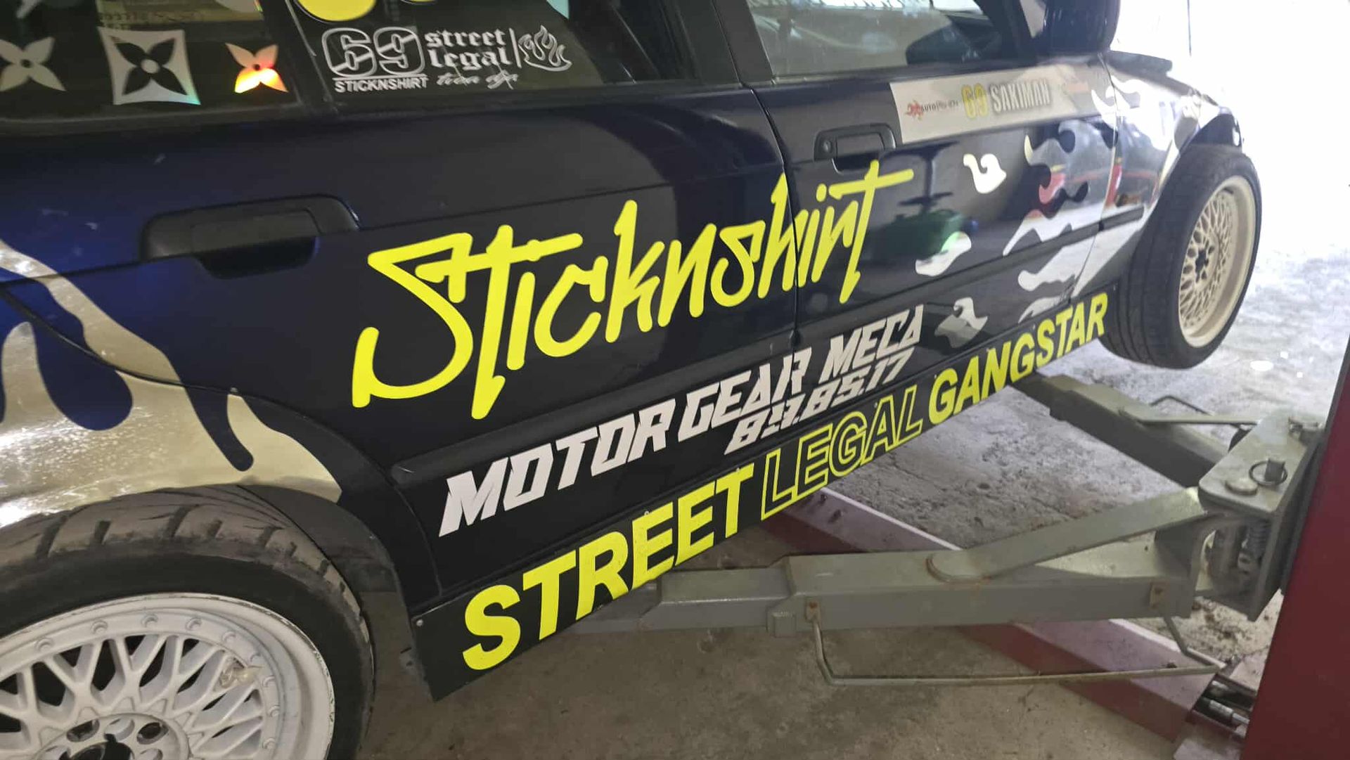 Car with decals, raised on a lift. 