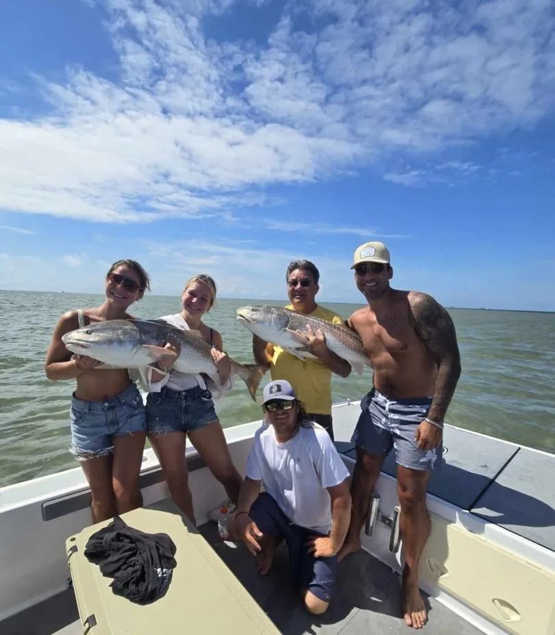 People on a boat holding up large fish, cloudy sky, sunny day on the water.