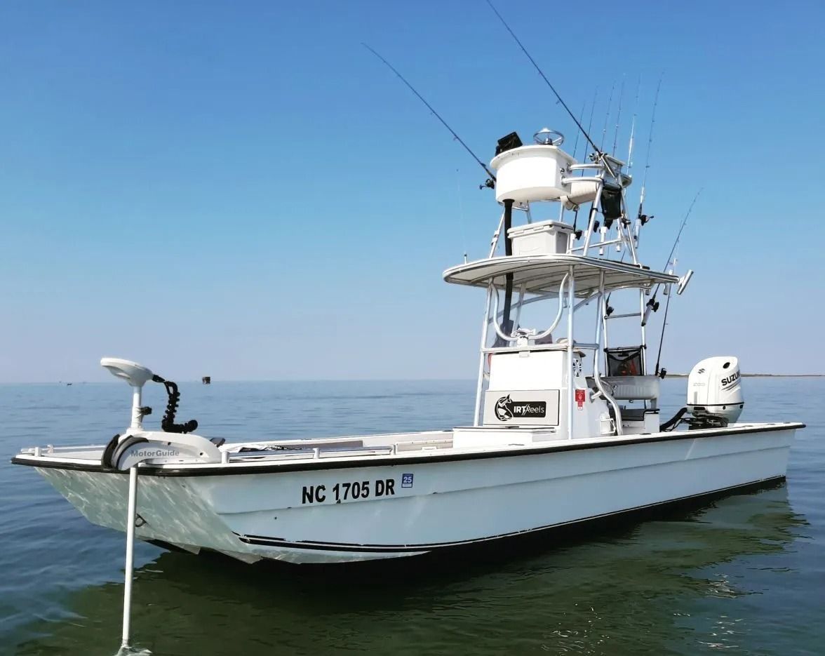 White fishing boat on water under a clear sky; North Carolina registration.