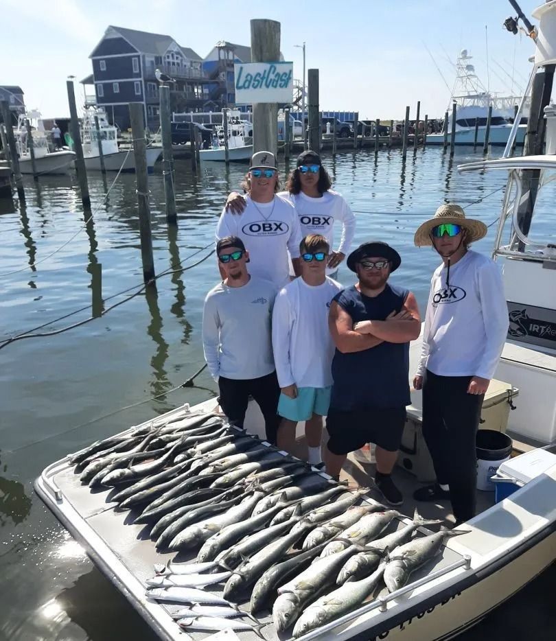 Group of people with a large fish haul on a boat at a marina.