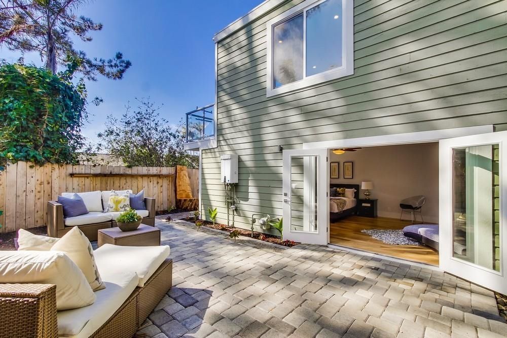 There is a patio with a couch and chairs in front of a house.