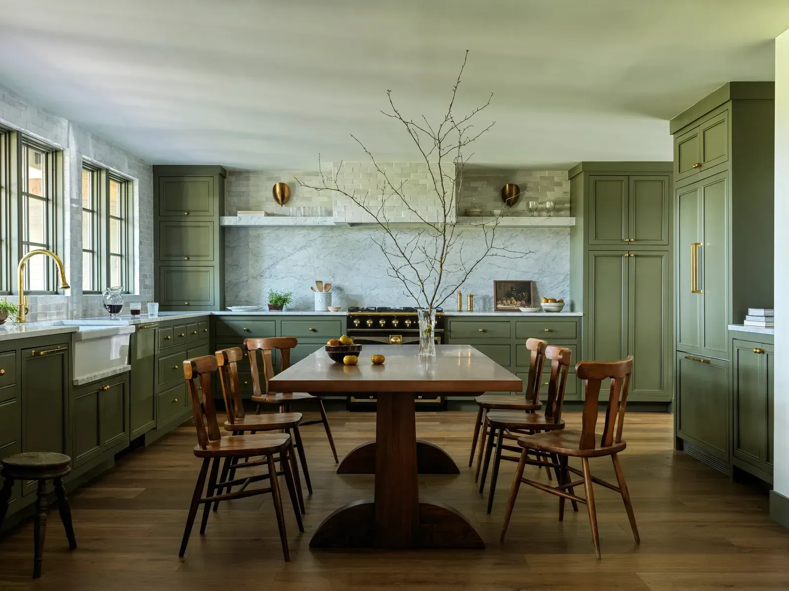 A kitchen with green cabinets and a wooden table and chairs.
