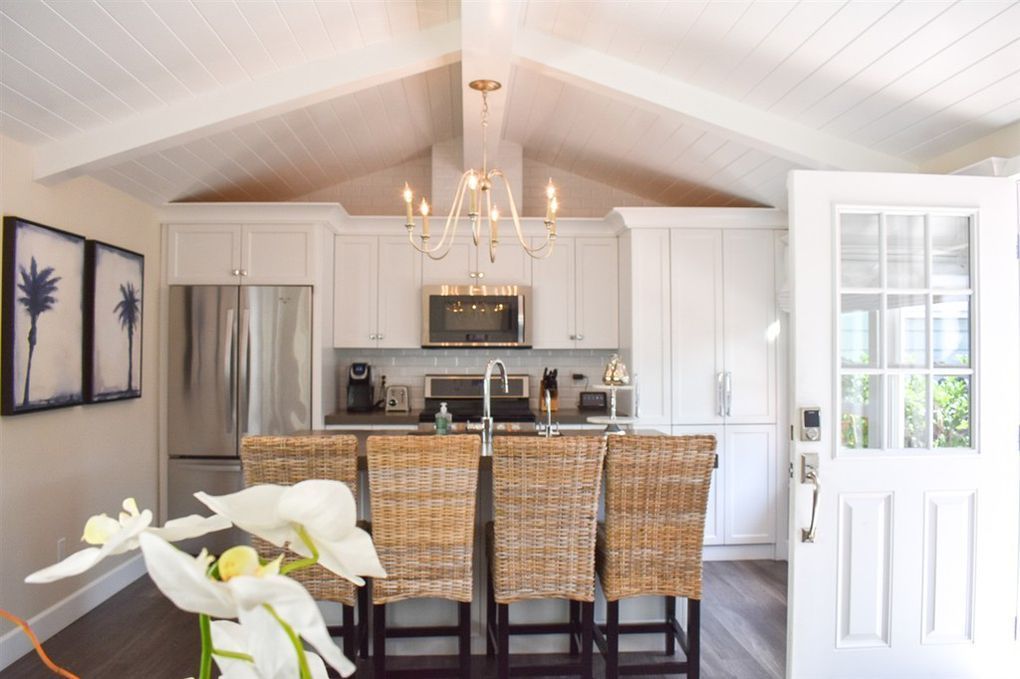 A kitchen with white cabinets and wicker chairs