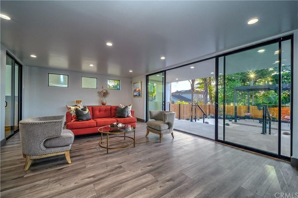 A living room with a red couch , chairs , and sliding glass doors.