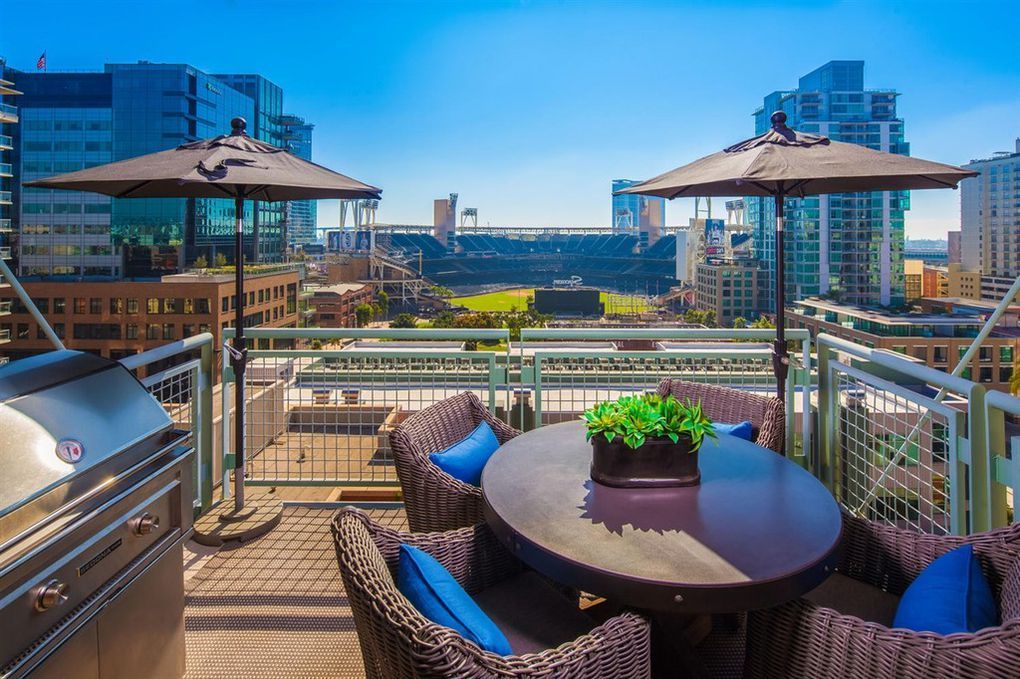 There is a table and chairs on the balcony with umbrellas.