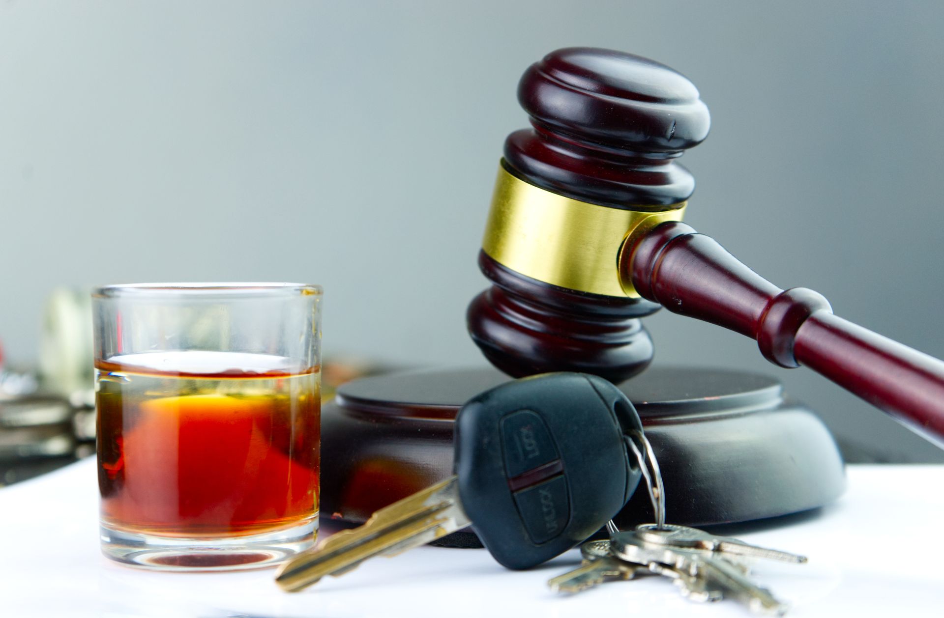 Gavel, car keys, and a glass of liquor on a table, symbolizing a DUI case. Gavel, car keys, and a glass of liquor on a table, symbolizing a DUI case.