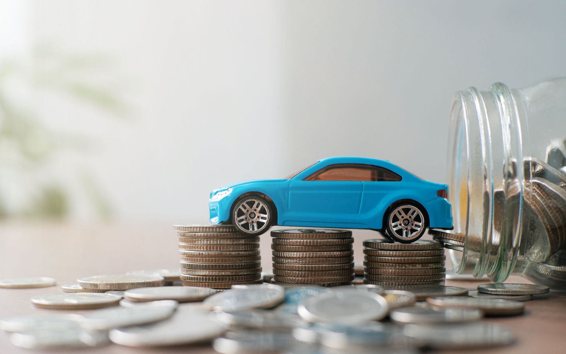 A toy car is sitting on top of a pile of coins.