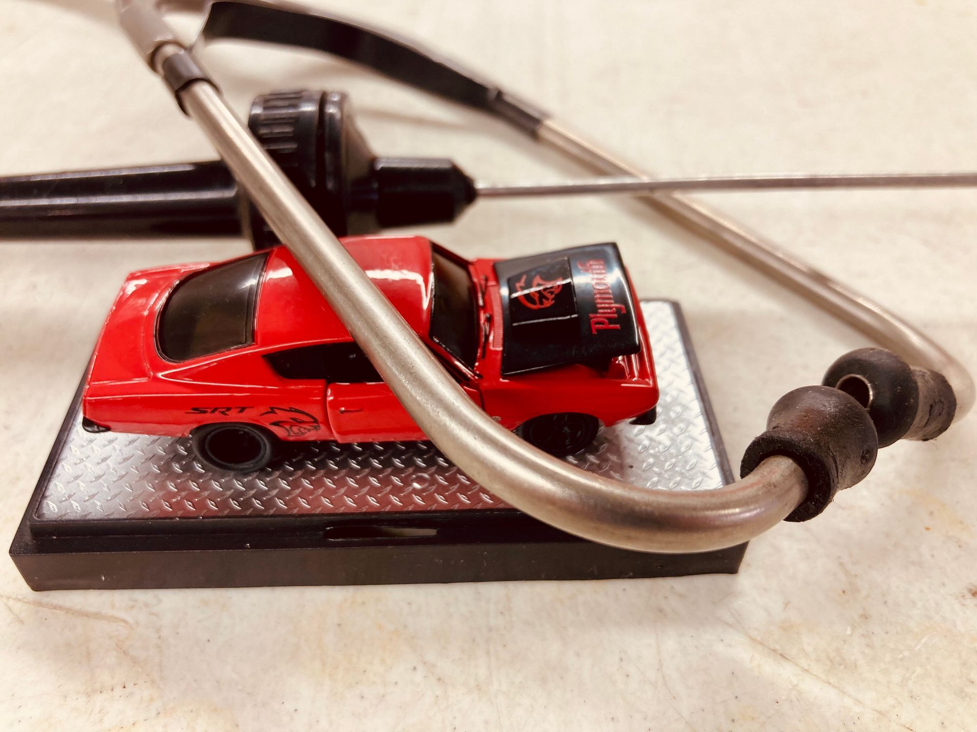 A red toy car is sitting next to a stethoscope
