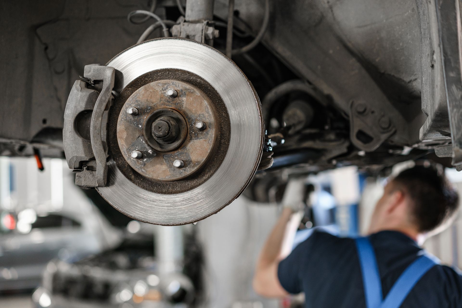 A man is working on the brake disc of a car in a garage.