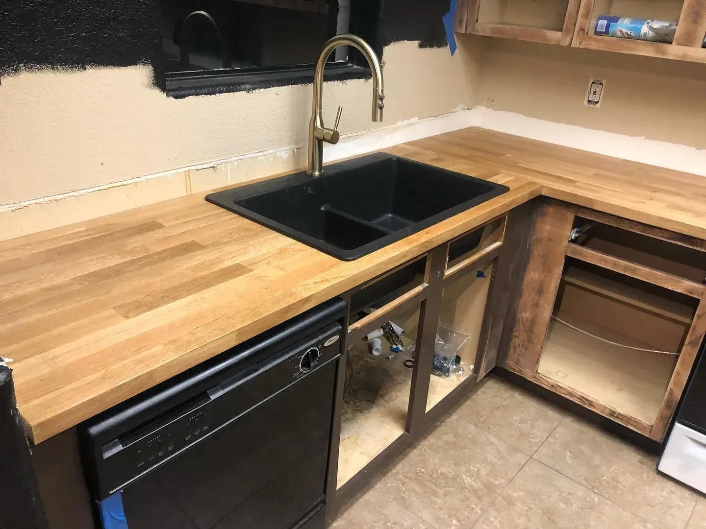 Modern kitchen counter with black sink, wooden countertop, and open cabinet space underneath. Modern kitchen counter with black sink, wooden countertop, and open cabinet space underneath.