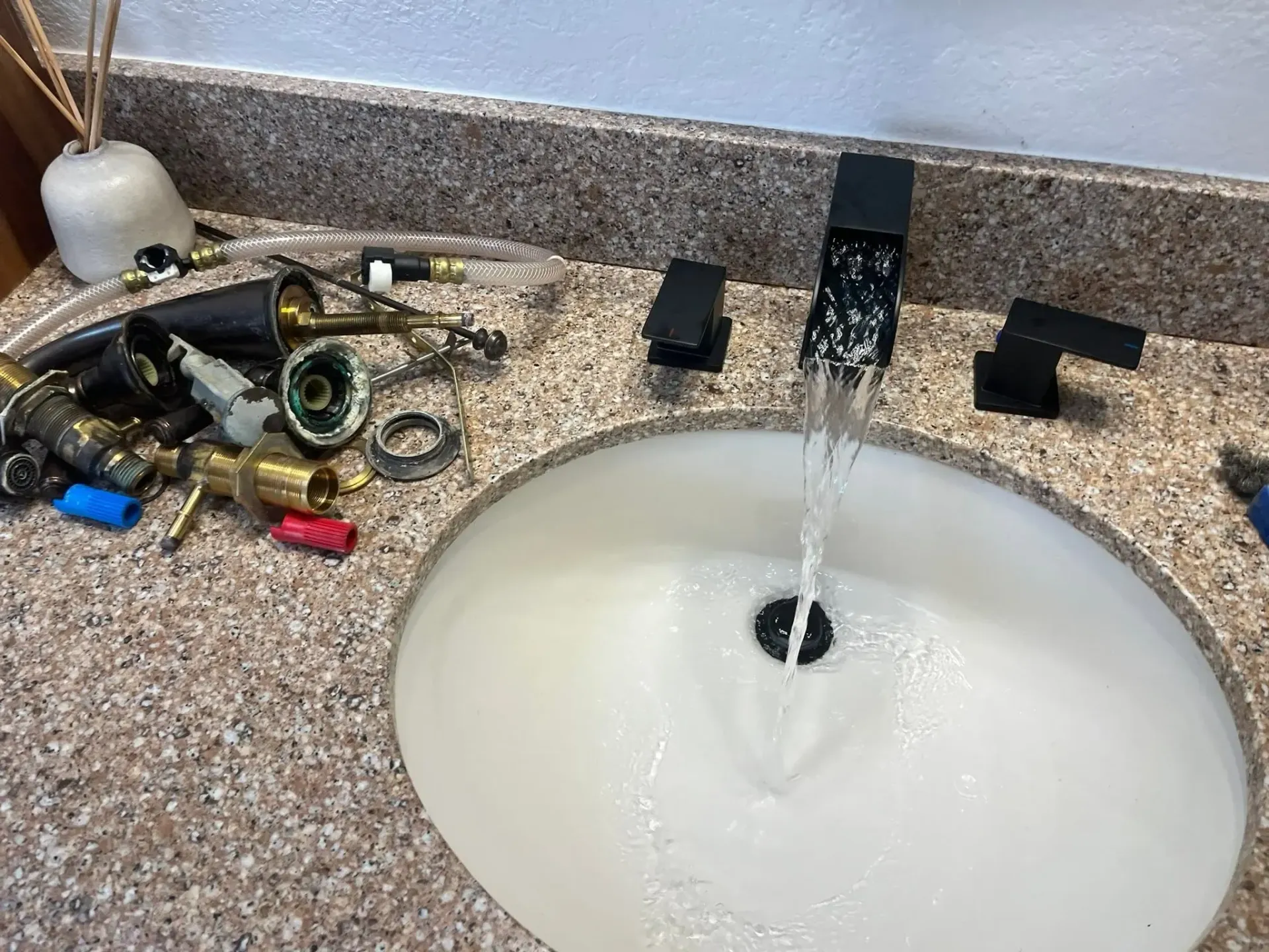 Bathroom sink with running faucet, soap dispenser, and scattered tools on the counter Bathroom sink with running faucet, soap dispenser, and scattered tools on the counter