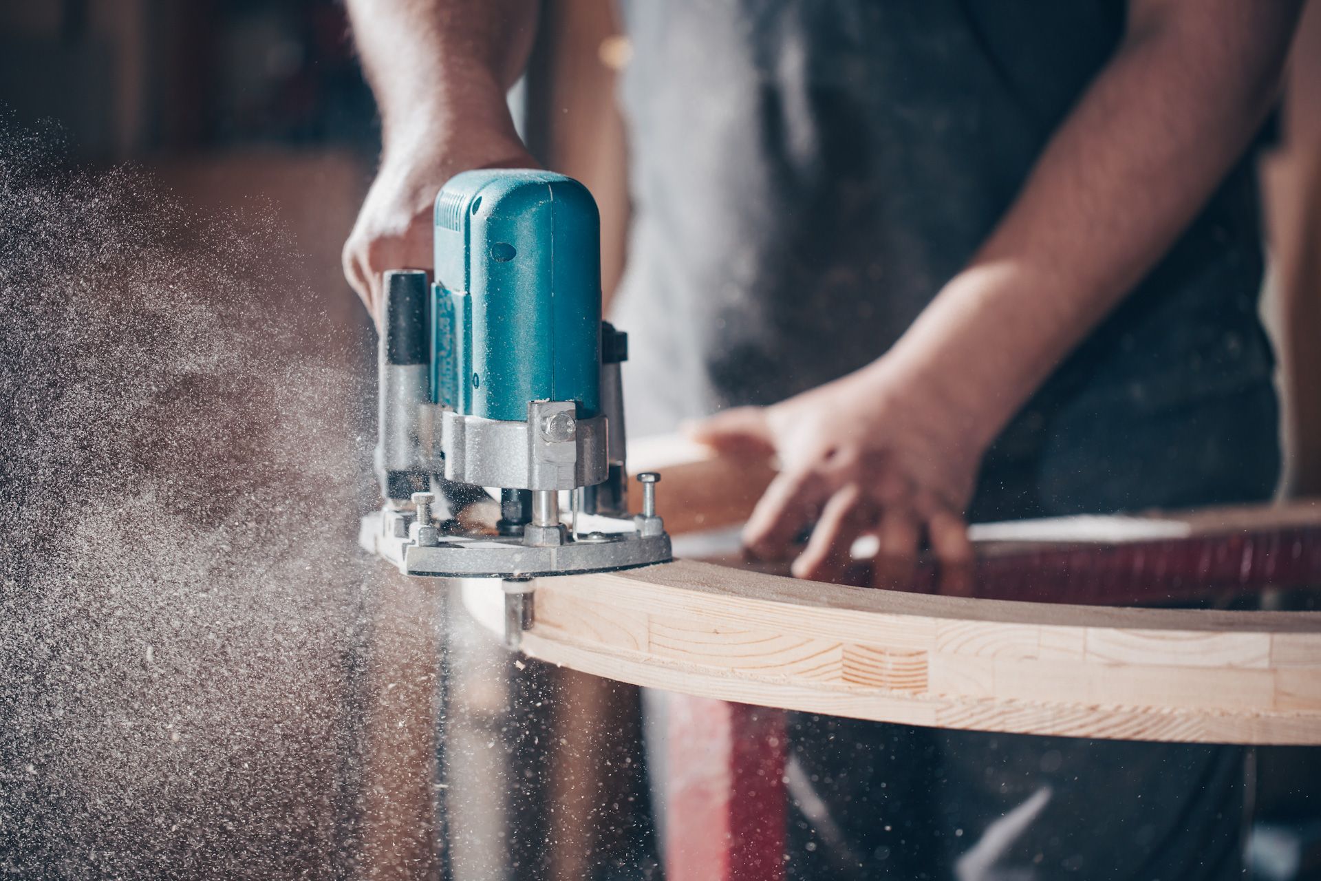 A man is using a router to cut a piece of wood.