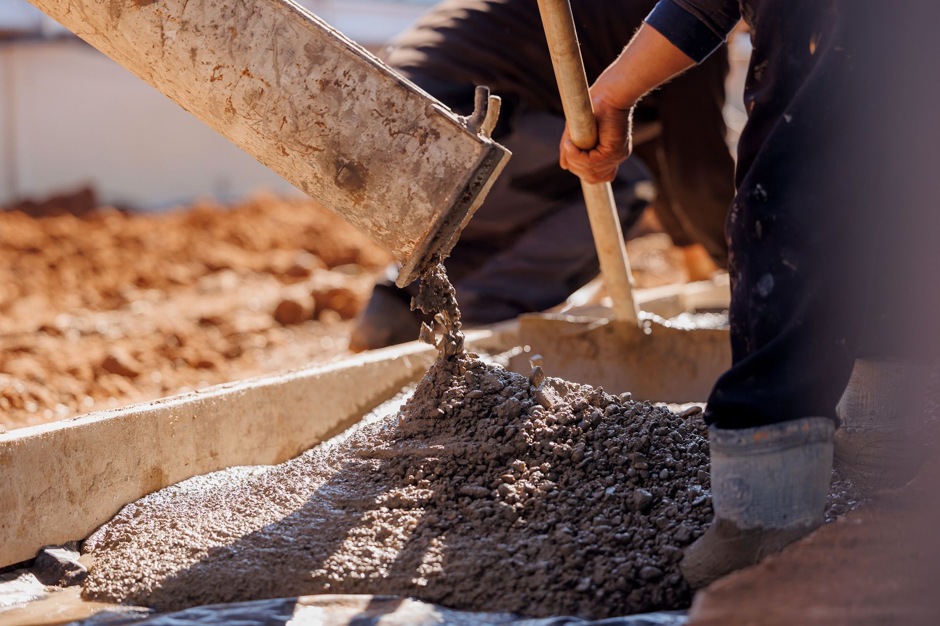 A man is pouring concrete into a bucket with a shovel.