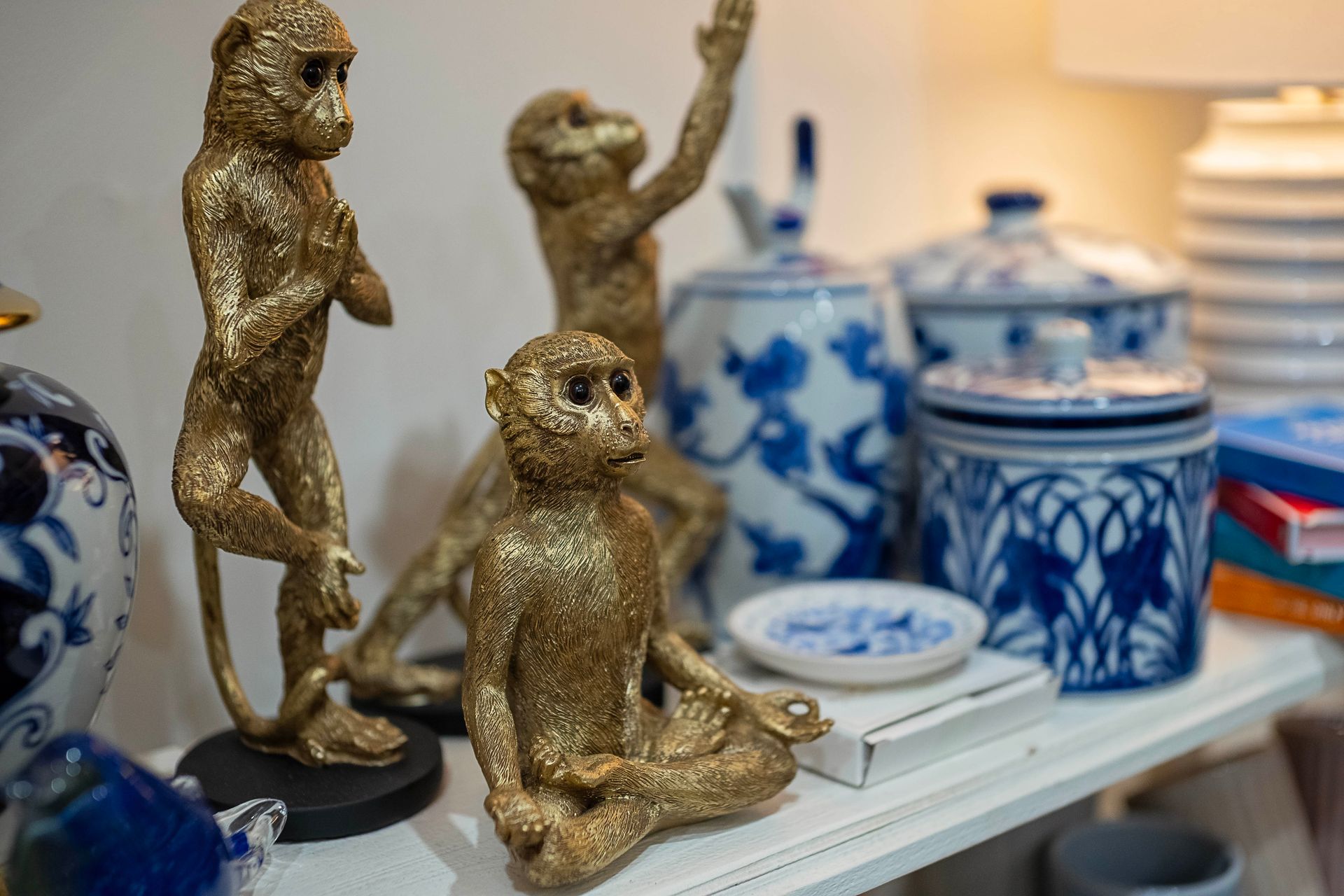 Gold monkey statues and blue and white ceramic jars on a shelf.