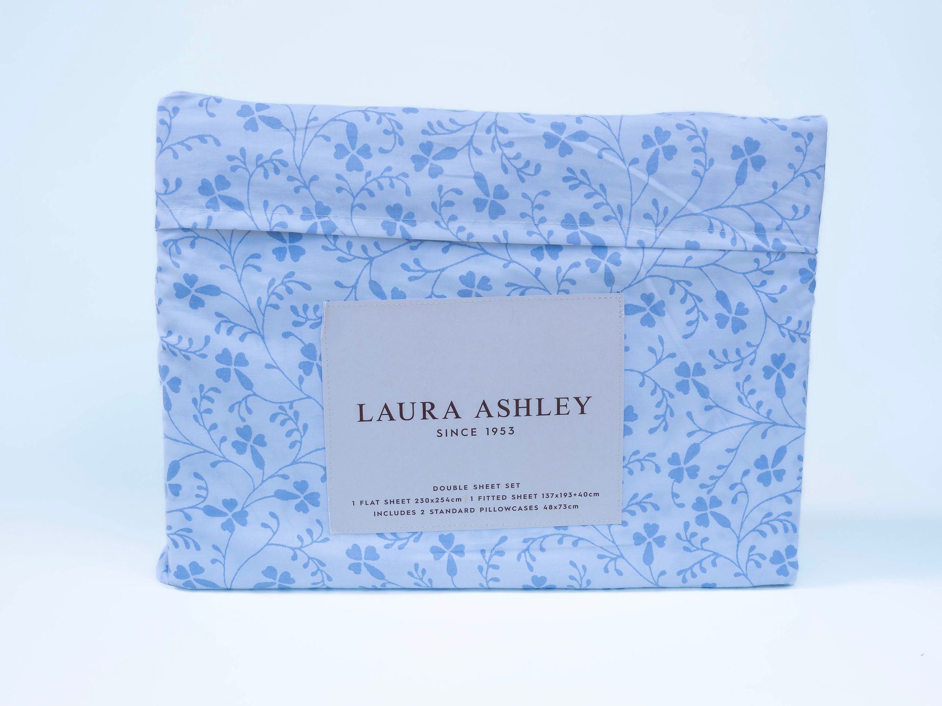 Folded bed sheet set in blue floral print with a Laura Ashley label.