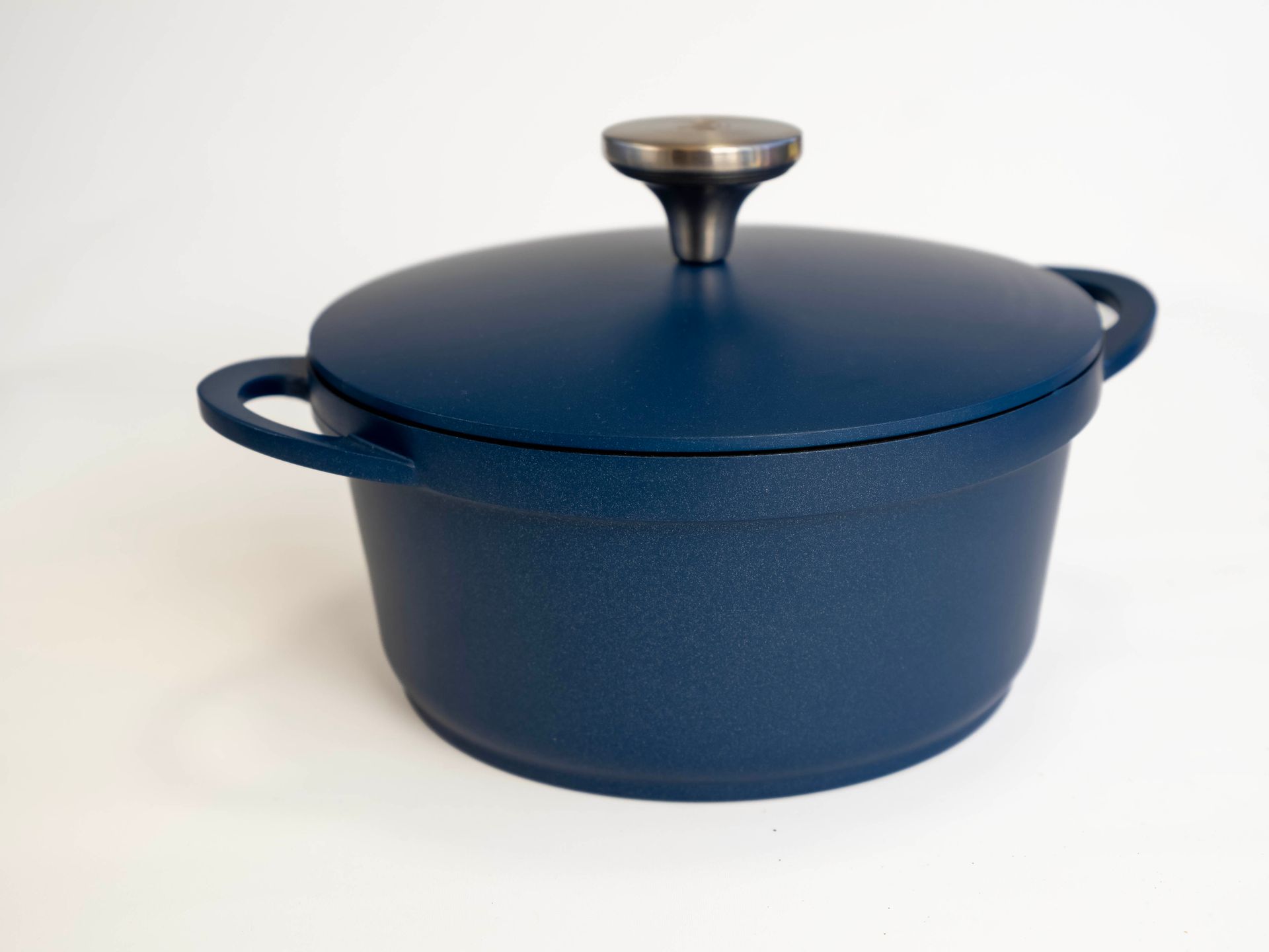 Green cast iron Dutch oven with lid and side handles.