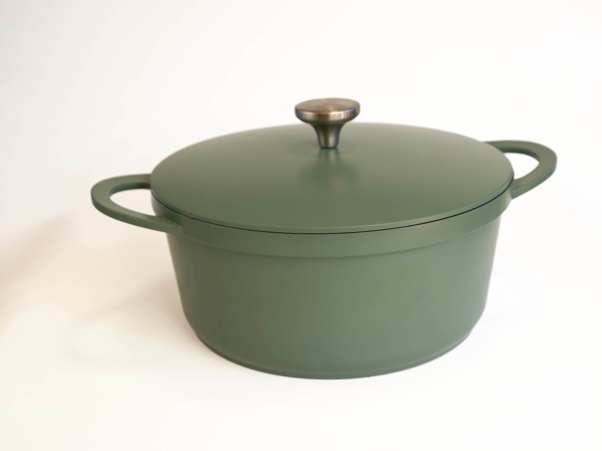 Green cast iron Dutch oven with lid and side handles.