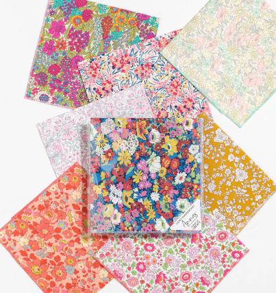 Colourful floral patterned fabric squares arranged on white surface.