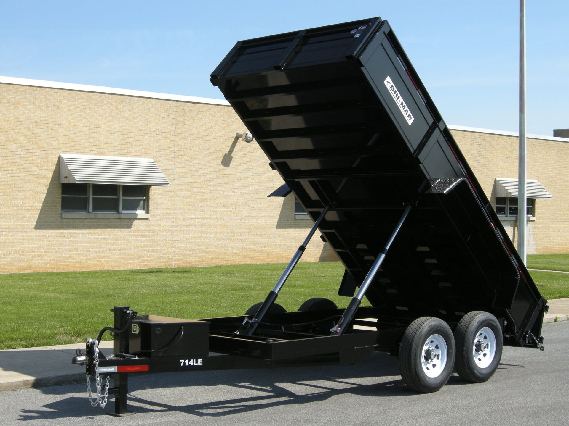 A dump trailer is parked in front of a brick building